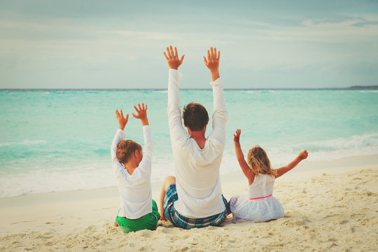 father with little son and daughter having fun on beach