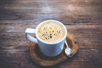 Closeup image of a white cup of hot coffee on wooden table background in vintage cafe