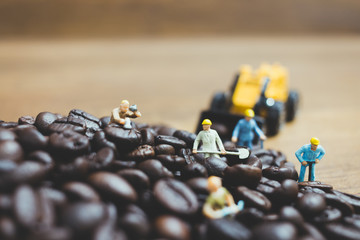 Miniature people working on roasted coffee beans