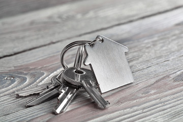 Keys to house with keychain on white wooden background