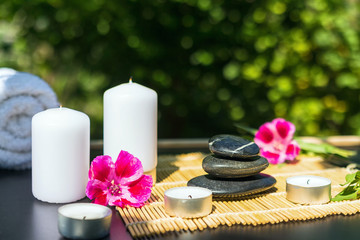 Candles, flowers, stones on a background of greenery for spa massage relaxation