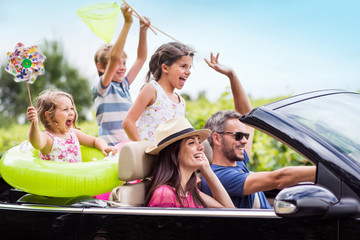 A family, in a convertible car, goes on holiday to the sea.