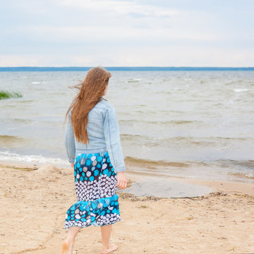 portrait of a beautiful young girl Goes into the distance. Teen girl On the beach. freedom and peace concept. Back view