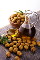 Bottle virgin olive oil and oil in a bowl with some olives