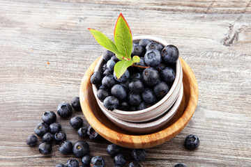Juicy and fresh blueberries with green leaves on rustic table.