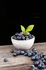 Juicy and fresh blueberries with green leaves on rustic table.