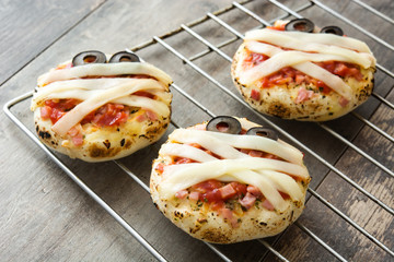 Halloween mummies mini pizzas on wooden table.
