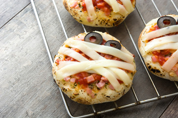 Halloween mummies mini pizzas on wooden table.
