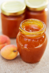 Apricot jam in glass jars with fresh fruit on a table