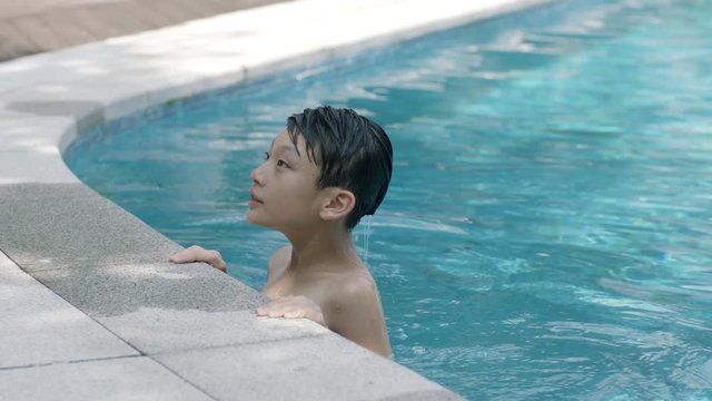 close up of Asian boy raising his head from swimming pool in slow motion