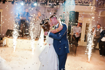 Newly married couple dancing on their wedding party with heavy smoke, multicolored lights and...