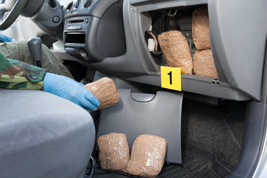Police officer holding drug package found in secret compartment of a car