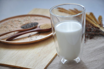 Glass of Milk with Spoon of Grains Seed on Wooden Plate
