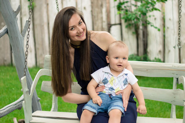 Fototapeta premium Happy woman playing with baby that siting on her knees