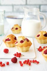 Wooden box with things for a picnic. Raspberry, muffins, milk, a notebook and wild flowers
