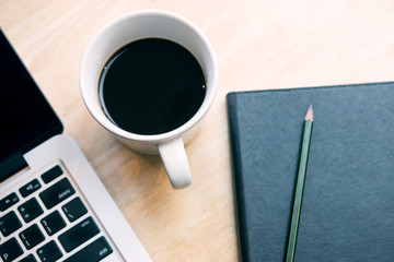 Notepad, laptop and coffee cup on wood table