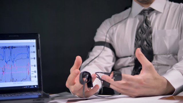A man takes shaking breaths during a polygraph test.