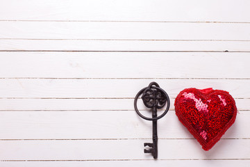 Red decorative  heart and key on  white  wooden background.