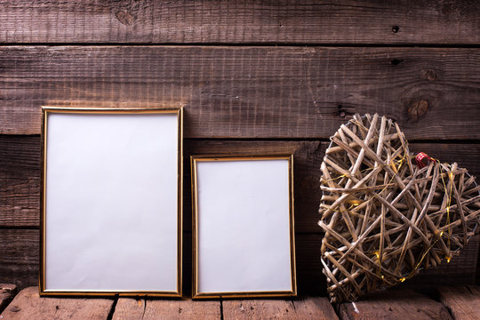 Two empty  golden frames differenr sizes  and decorative heart with fairy light