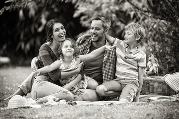 Cheerful family sitting on the grass during un picnic in a park