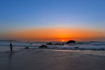 Atardecer; el mar tira de una ni&ntilde;a pero ella es m&aacute;s fuerte.