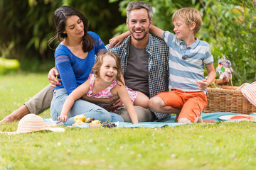 Fototapeta premium Cheerful family sitting on the grass during un picnic in a park