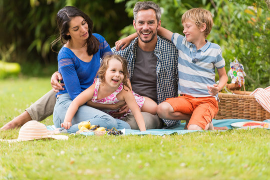 Cheerful family sitting on the grass during un picnic in a park