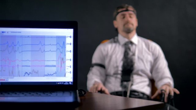 A man deeply breathing close to a polygraph data screen. 