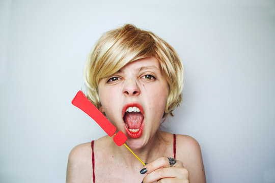 Mujer joven y rubia gritando con un signo de exclamaci&oacute;n junto a su cara