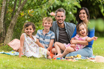 Fototapeta premium Cheerful family sitting on the grass during un picnic in a park