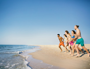 Group of friends run to the sea. Concept of summertime