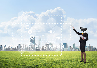 Camera headed woman standing on green grass against modern cityscape