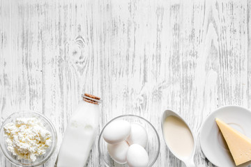 Farm dairy products. Milk, cottage, eggs, cheese on light wooden background top view copyspace