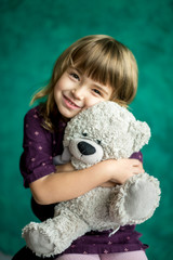 Happy little girl hugs a toy teddy bear