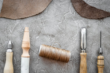 Leather craft tools on grey stone background top view copyspace