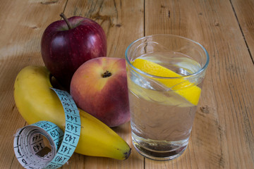 Water with lemon, fruits and measuring tape