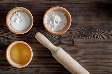 Put the dough. Flour, salt, oil and rolling pin on dark wooden table background top view copyspace
