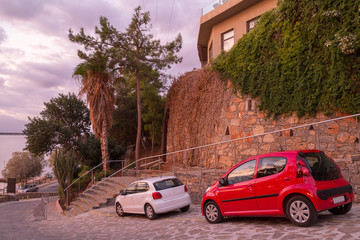 Two small cars near a stone wall on the shore of the Gulf of Mirabello. Crete. Greece