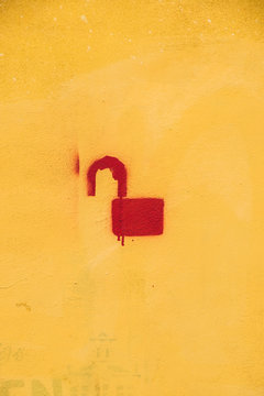 Unlocked Lock Stencil Graffiti on Yellow Plaster Wall