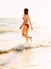 Fototapeta na wymiar Beautiful woman with perfect body in red swimwear standing up on the beach, wearing stylish bikini
