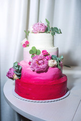 A beautiful home wedding four-tiered cake decorated with pink roses and leaves in a rustic style