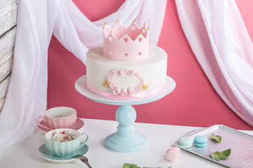 Cute pink cake with a crown on the table to the birthday for a Princess