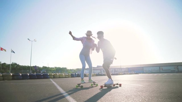 Young attractive mixed race couple riding skateboards and having fun, slow motion