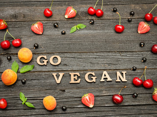 Go vegan inscription on a black wooden background, fruit. Food Concept