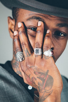 Close up of a stylish black man wearing rings on a tattooed hand