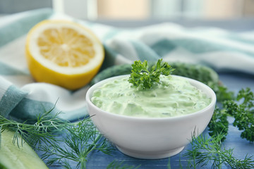 Delicious yogurt sauce in bowl with ingredients on wooden table