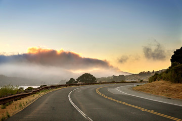 Paved road curve to the right, sunset, cloudy sky