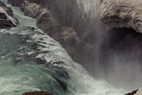 water rushing over an icy waterfall and falling into a gorge