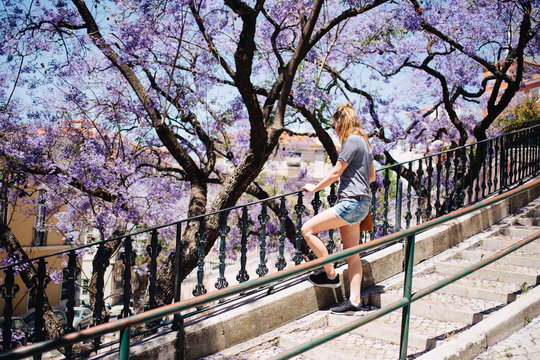 Young woman standing on a stairs in front of a jacaranda tree