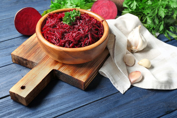 Grated beet in bowl on wooden background